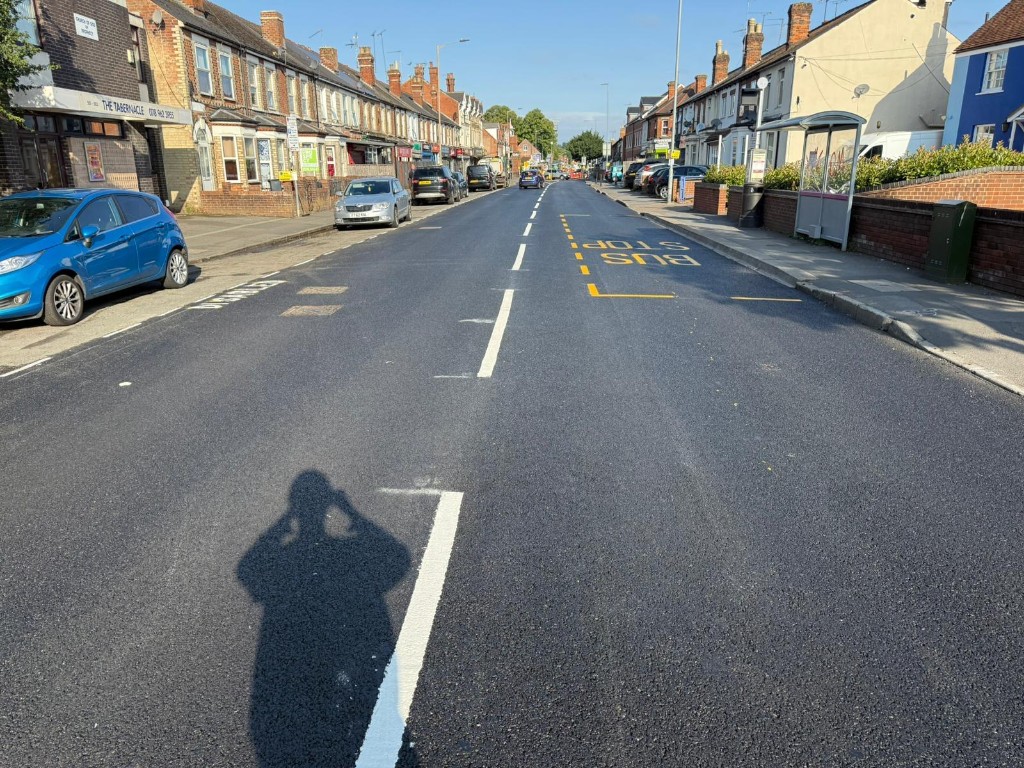 Resurfaced urban road with lane markings and bus stop yellow hatched bays
