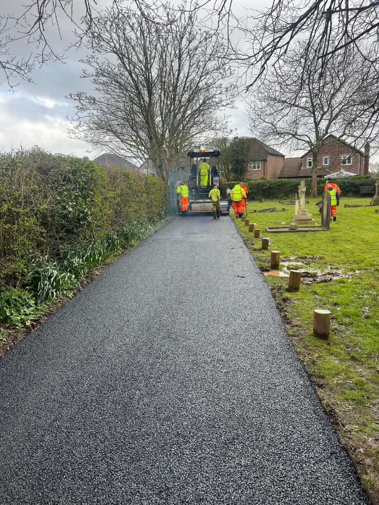 Machine-laid asphalt footpath with paving crew on site