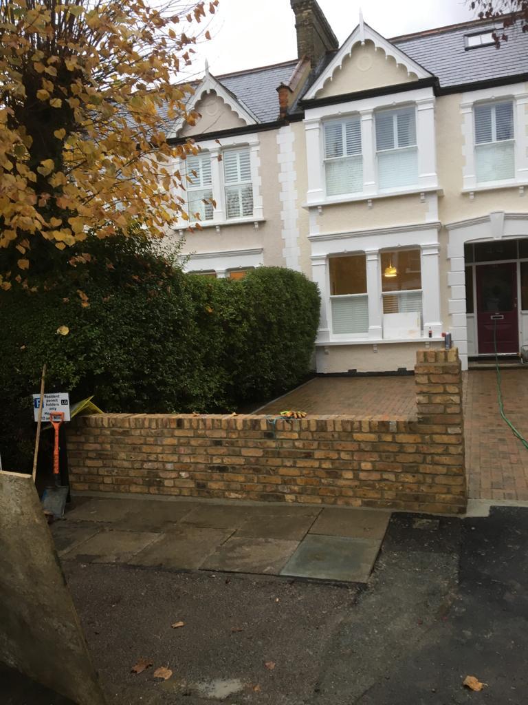 Buff brick garden wall with quarter brick pillar beside a cream rendered period house