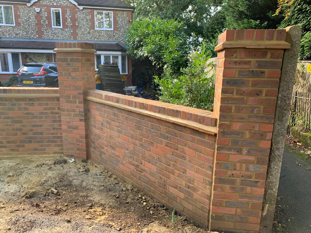 Brick pillars and wall sections with stone coping and recessed iron gate