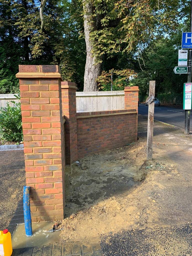 Angled view of multi-tone brick pillars connected by a low wall with soldier-course coping