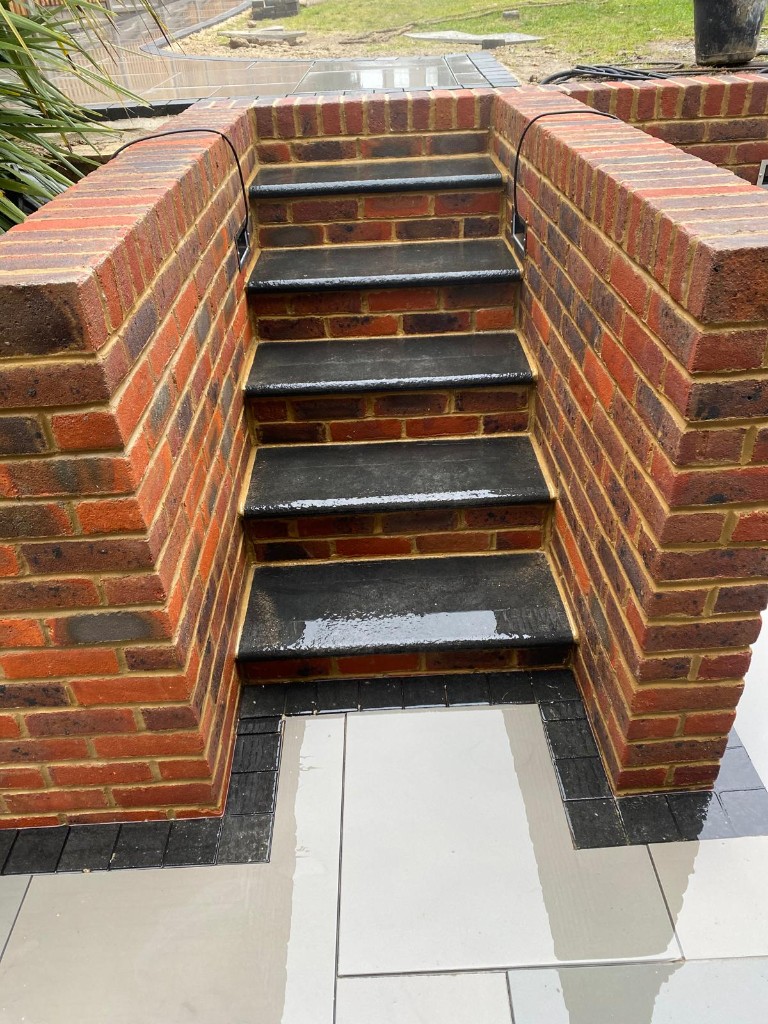 Multi-tone red brick boundary wall and pillars with decorative coping at a residential plot