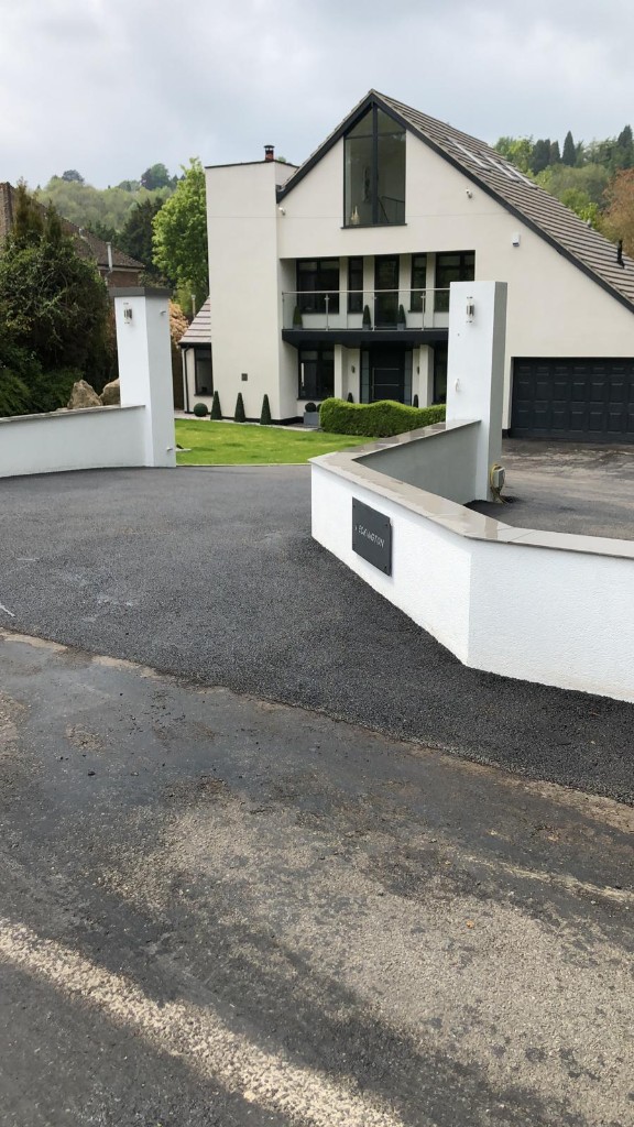 Domestic driveway entrance with rendered pillars and fresh dark tarmac