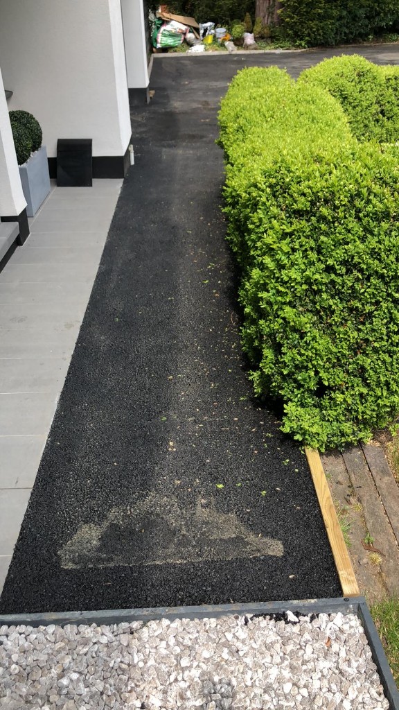 Tarmac driveway entrance with hedge, gravel detail and tall rendered piers