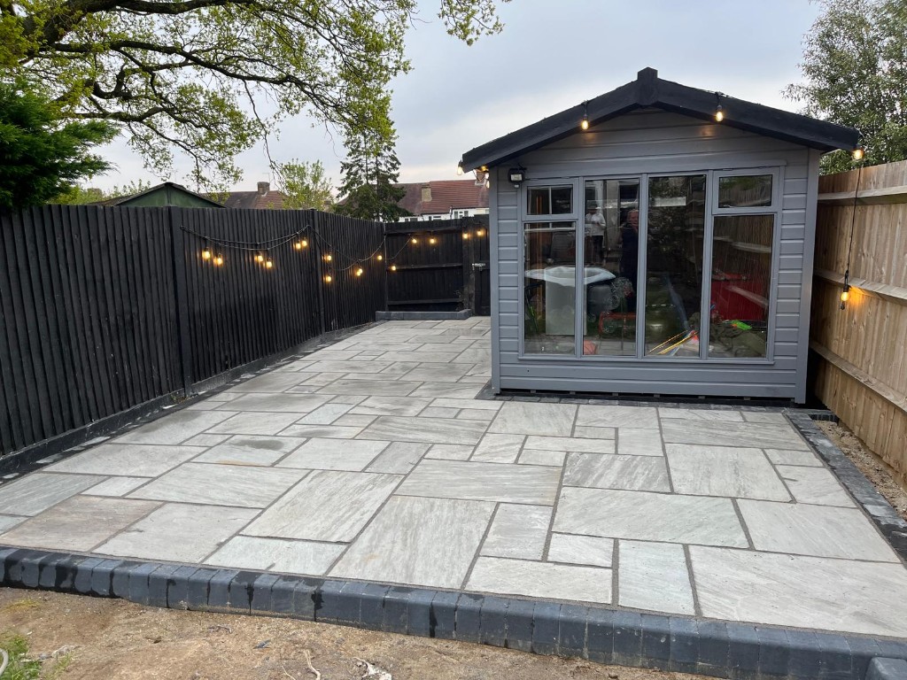 Contemporary rear patio with pale grey stone paving and horizontal timber fencing