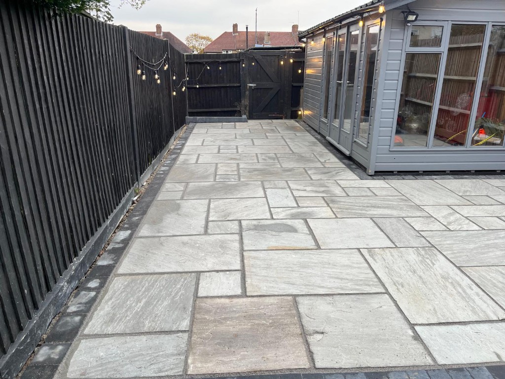 Resin-bound driveway with flush service covers framed by grey paving setts