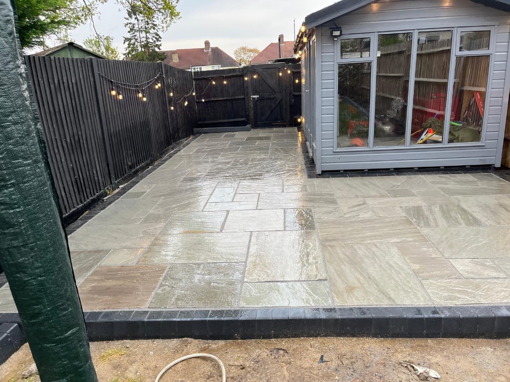 Tan resin-bound terrace with grey block edging and low rendered boundary wall