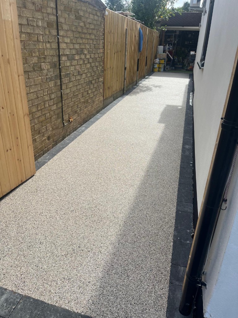 Elevated view of new grey stone patio beside lawn, raised sleeper bed and play equipment