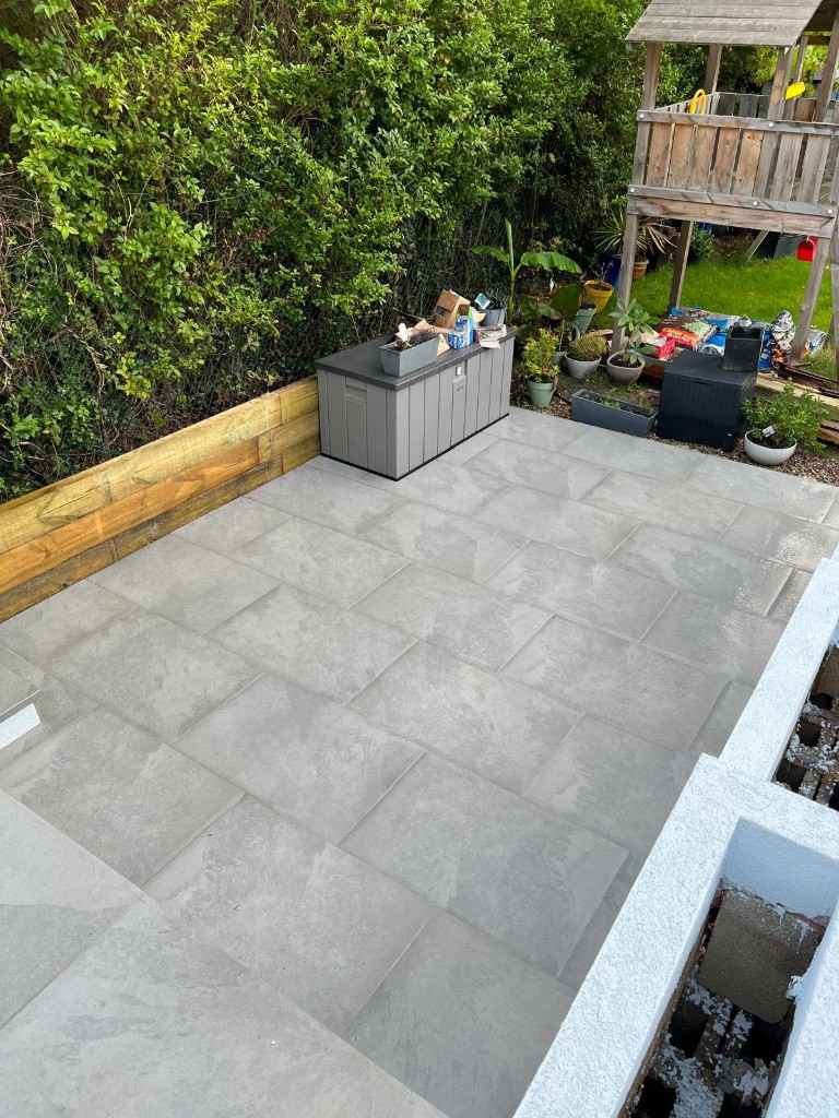 Random bond limestone-style patio with charcoal brick soldier course in a rear garden