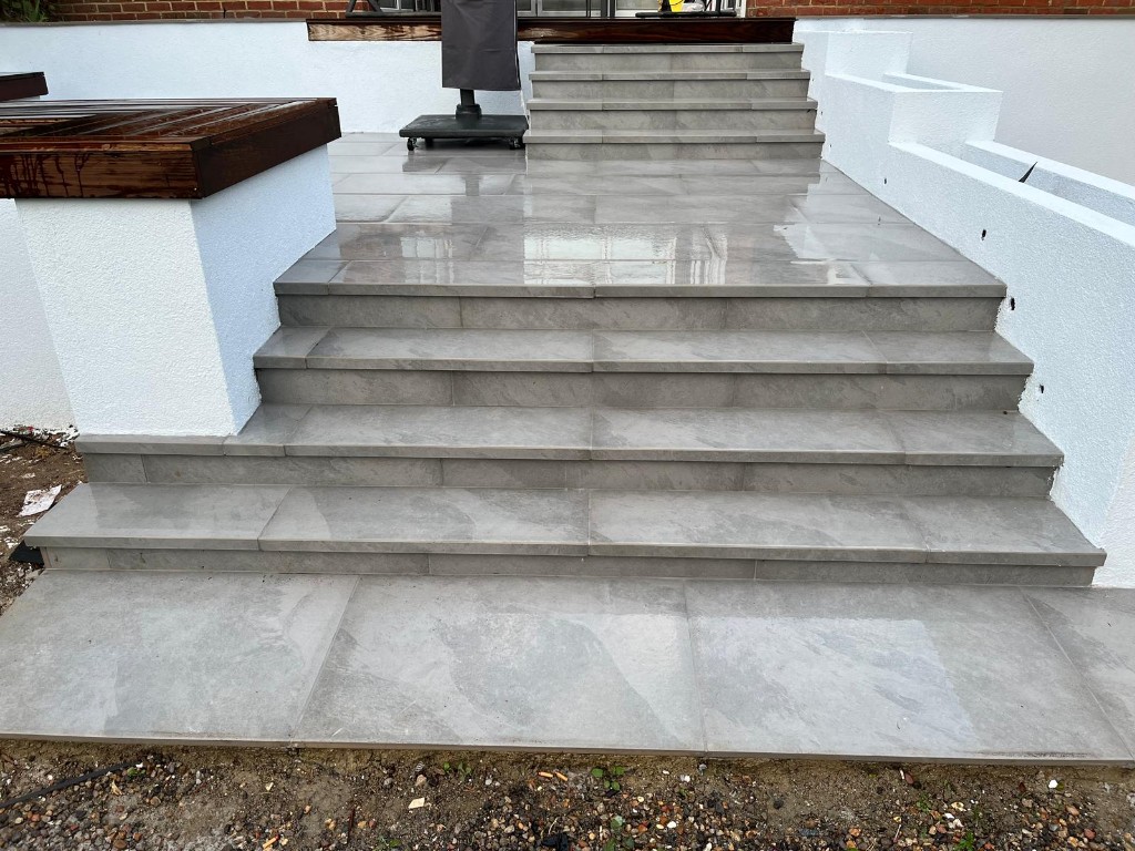 Split-level grey stone patio with sleeper retainers, steps and dense planting