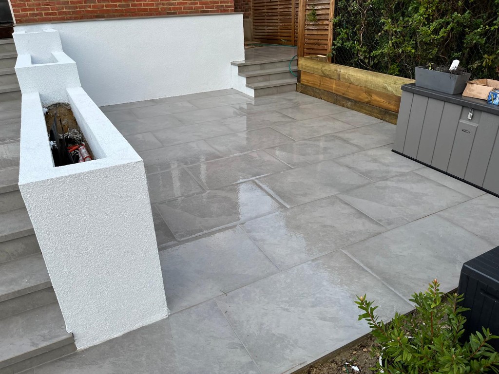 Raised patio with matching grey slab steps and white rendered planters