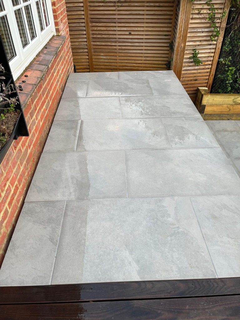 Long grey paved run beside red brick house wall and horizontal timber screening