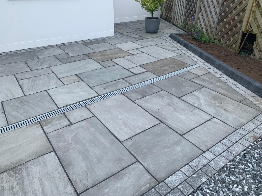 Stone paving with recessed linear metal drainage channel and sett margins