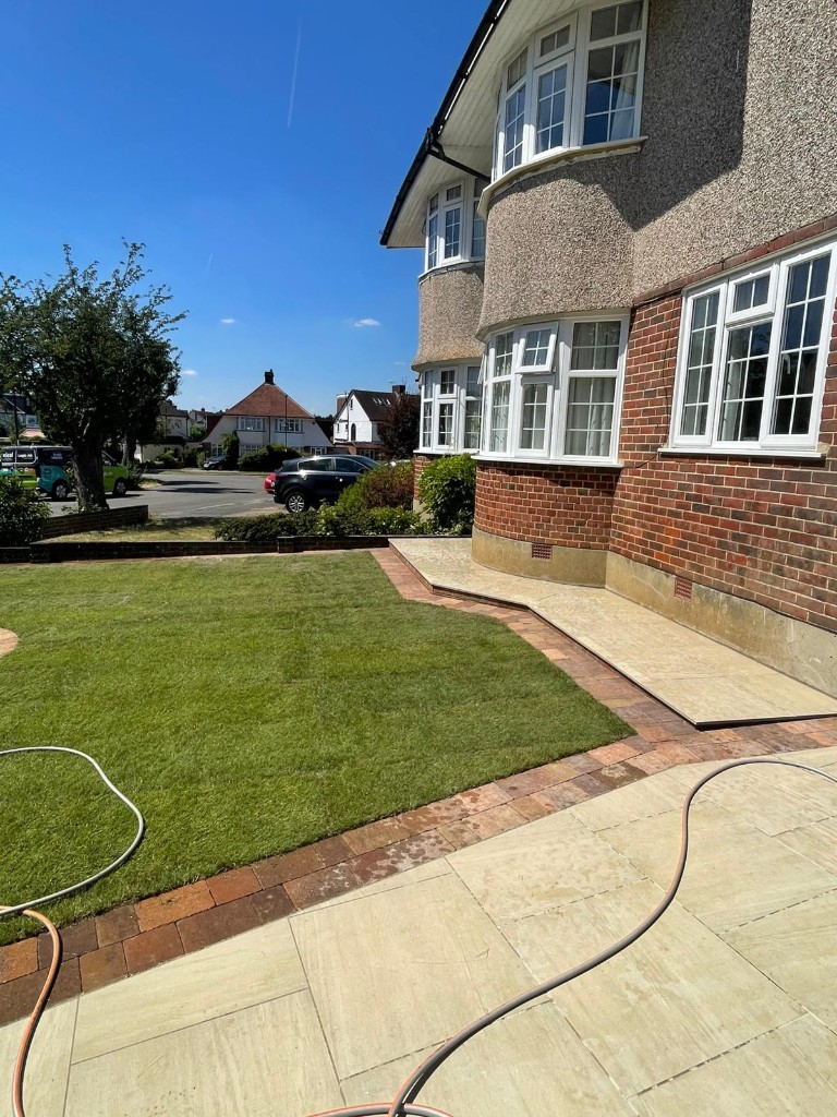 Wide stone patio with channel drain, gravel zone and planting bed