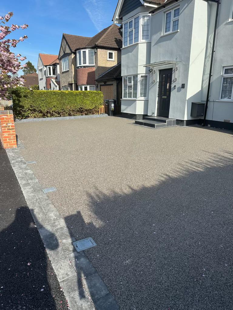 Residential driveway with charcoal block paving border and decorative lighter surfacing toward the house