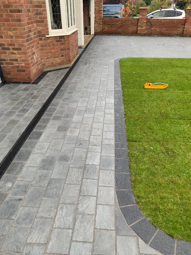 Block paving and lawn with charcoal edging and ACO drainage channel along the property