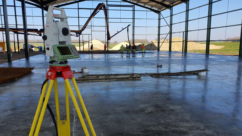Total station on tripod at civil engineering site during concrete slab works