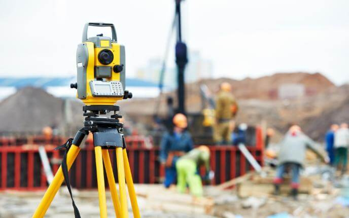 Surveying engineer using a total station on site for civil engineering setting out