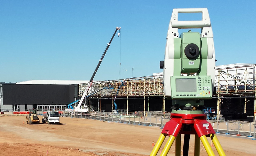 Total station on tripod at civil engineering site during large-scale structural works